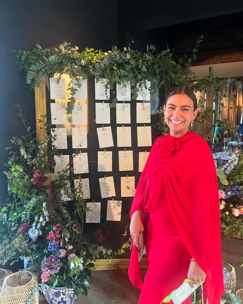 mujer con vestido rojo frente a una pared con plantas